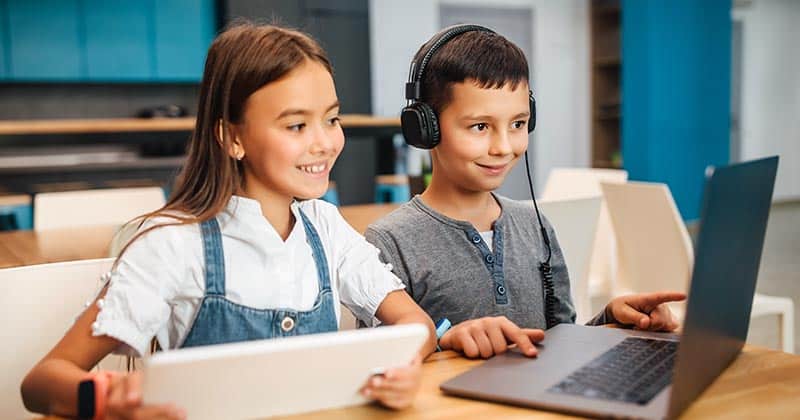 Students using a laptop and tablet in elementary school