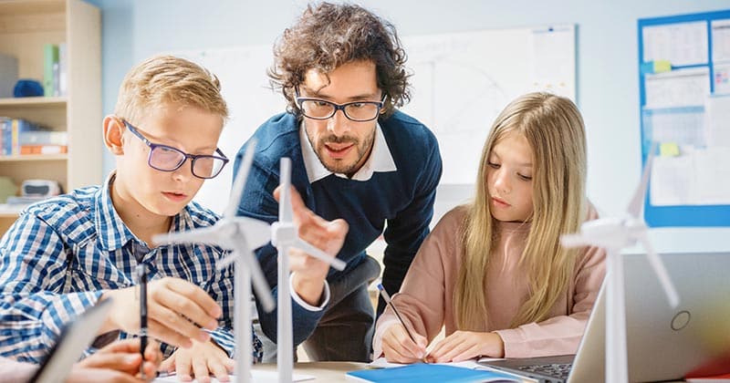 Teacher showing model wind turbines to students